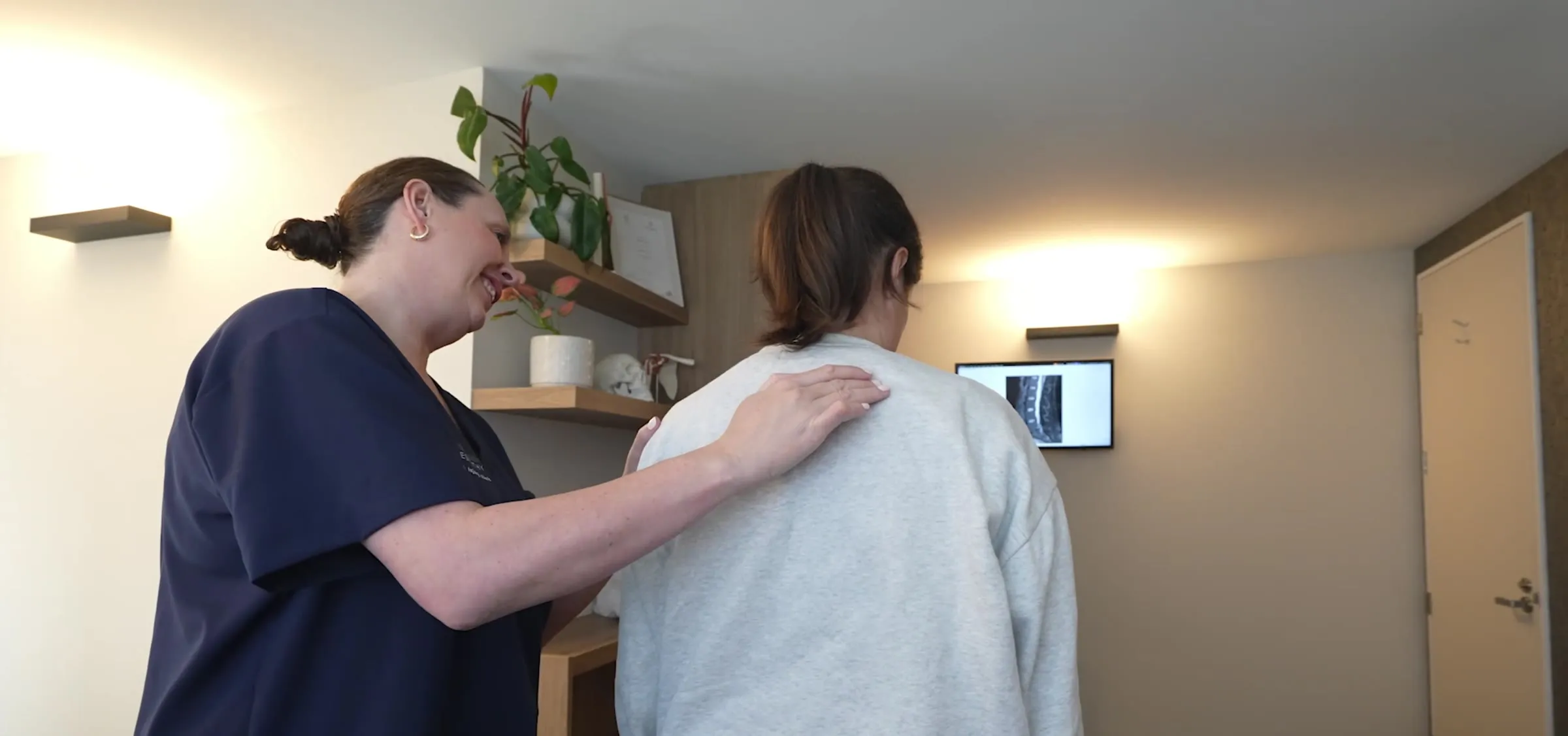 Lorraine Herity guiding a patient into the treatment room with a reassuring hand on their back