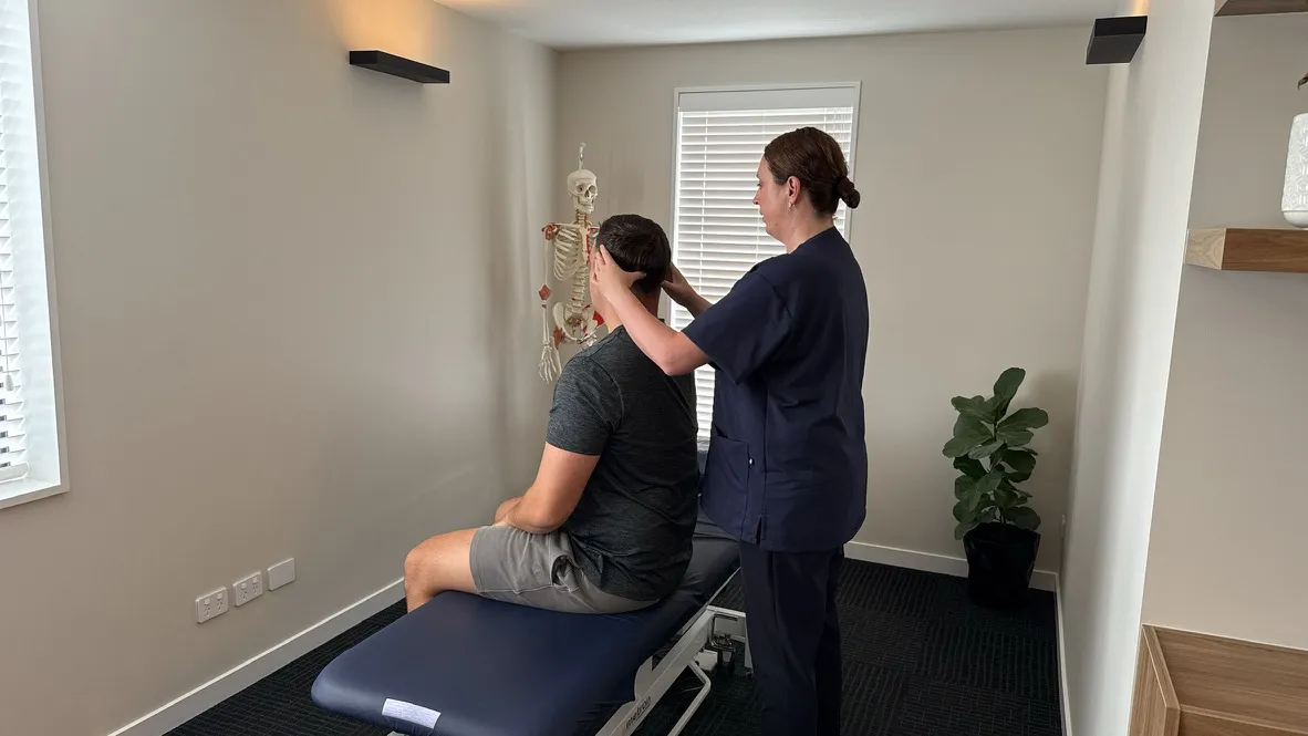 Lorraine Herity performing cervical osteopathic treatment on an adult male patient seated on a treatment bench