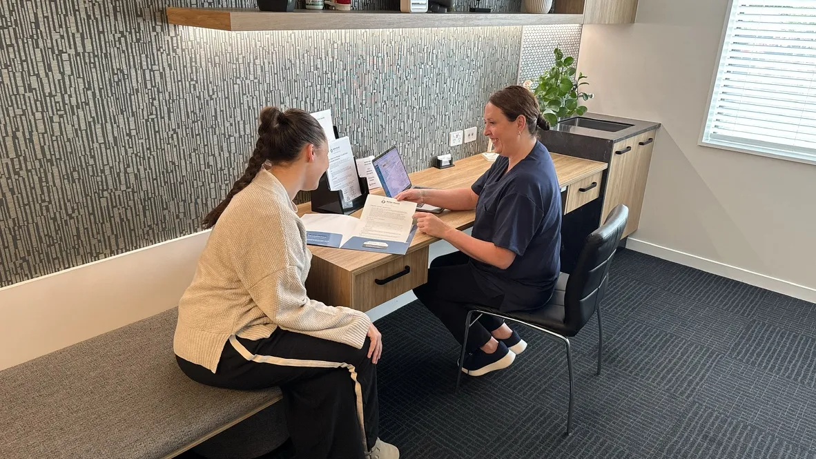 Lorraine Herity in consultation with an adult patient at her desk, reviewing assessment findings together