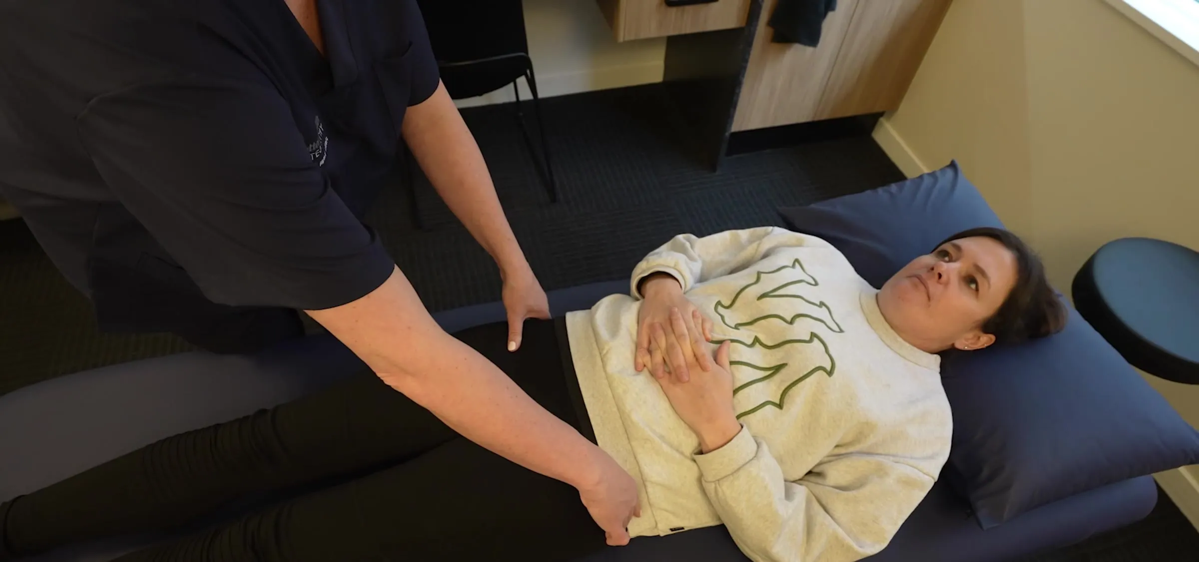 A patient lying comfortably on a treatment table while an osteopath reassures them