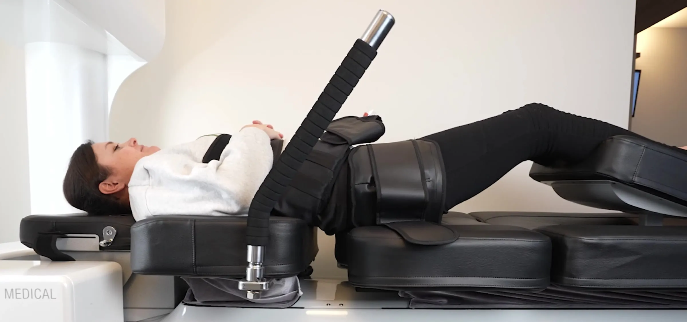 The padded support harness fitted around a fully clothed patient on the decompression table